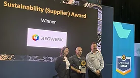 Picture of a man holding an award, standing between another man and a woman.