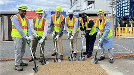 Picture of six men in safety vests and yellow hard hats with shovels