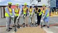 Picture of six men in safety vests and yellow hard hats with shovels