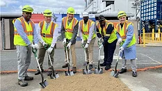 Picture of six men in safety vests and yellow hard hats with shovels