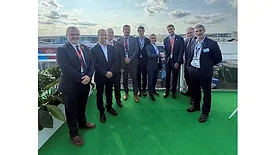 Picture of nine men in suits standing on the rooftop of a building