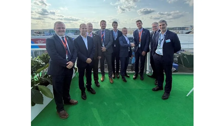 Picture of nine men in suits standing on the rooftop of a building