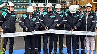 Picture of men in blue cutting a ribbon