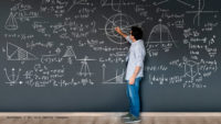 Photo of math teacher writing formulas on chalkboard