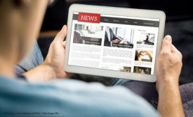 Photo of a person holding a tablet, reading a new story