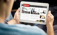 Photo of a person holding a tablet, reading a new story